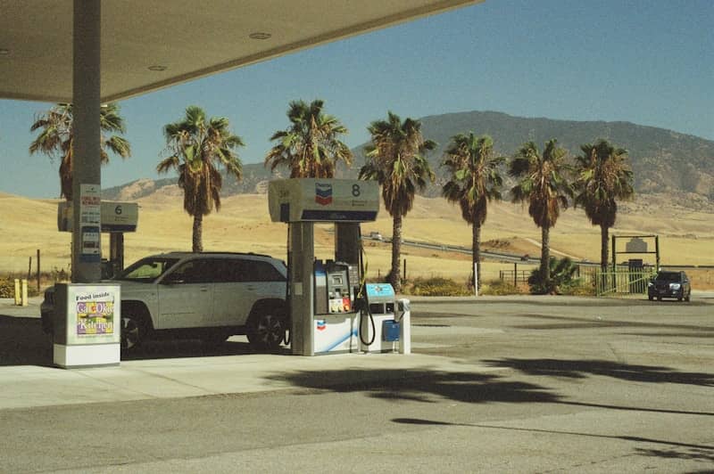 White suv at a gas station with palm trees