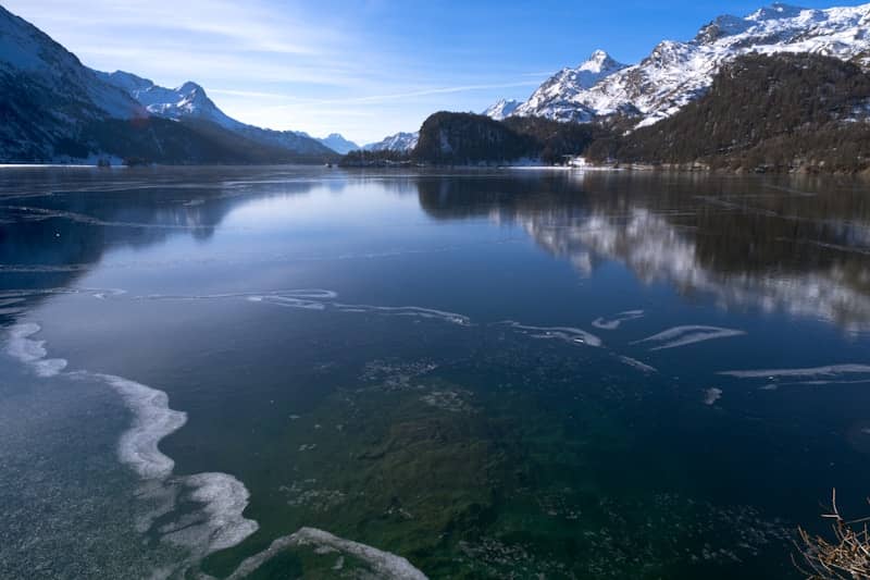 Frozen lake with snow-capped mountains and clear blue sky