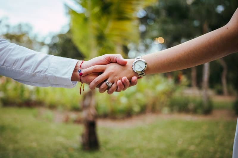 Two people shaking hands outdoors with rings