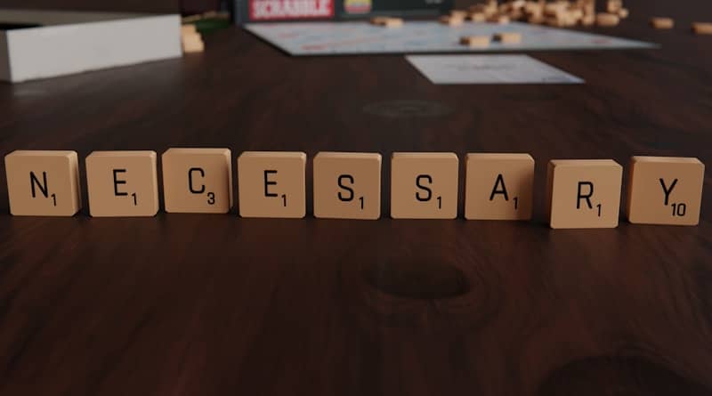 Scrabble tiles spelling the word "necessary" on a table.