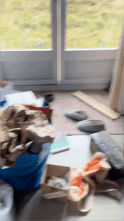 A sweeping gif of an extremely messy office with stuff EVERYWHERE. There’s a very cool orange wall though.