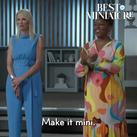 gif from Best in Miniature. White lady in blue jumpsuit standing. Black lady in colourful dress saying "make it mini" and close up of squeezing finger and thumb together to show mini. Words on bottom: Make it mini.