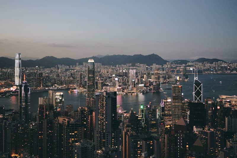 City skyline at dusk with illuminated skyscrapers and dark buildings.
