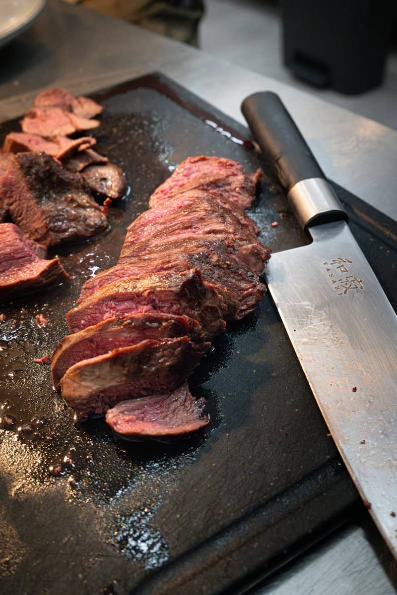 A steak being cooked on a grill with a knife