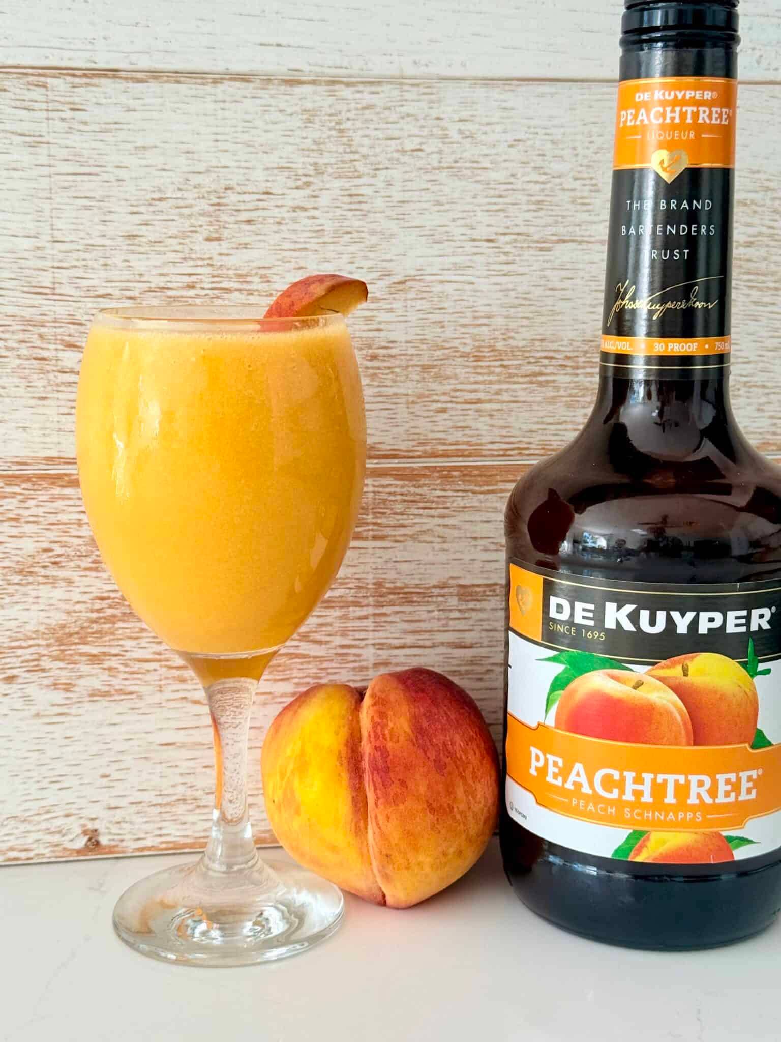 a peach schnapps slushie in a glass next to a peach