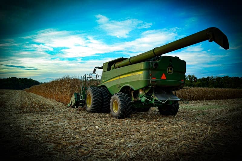 Green combine harvester working in a dry field.