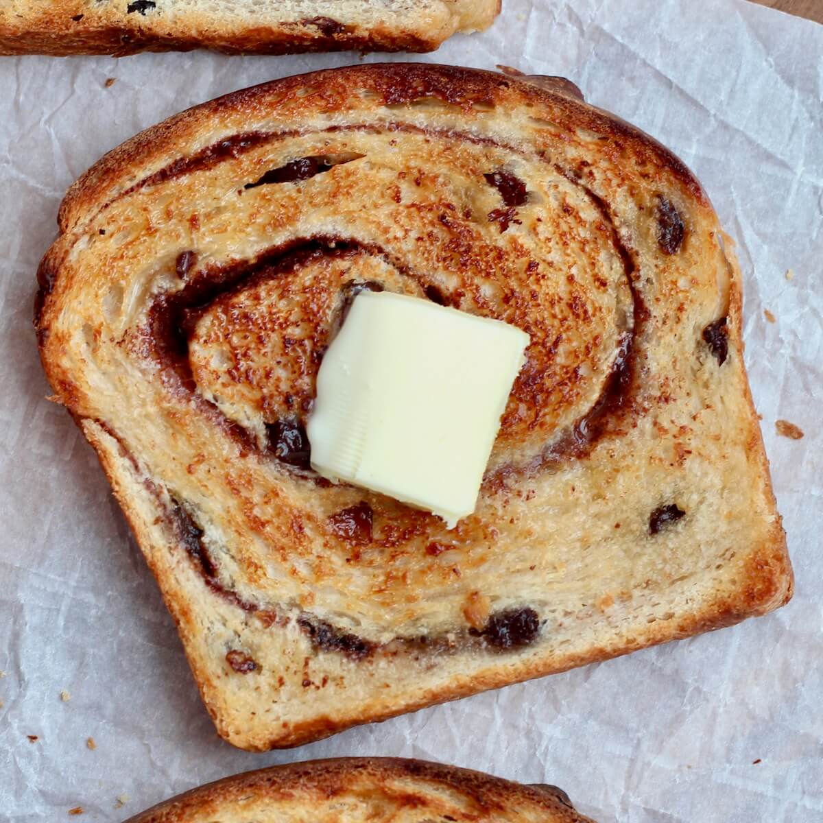 A piece of toasted cinnamon raisin sourdough bread with butter.