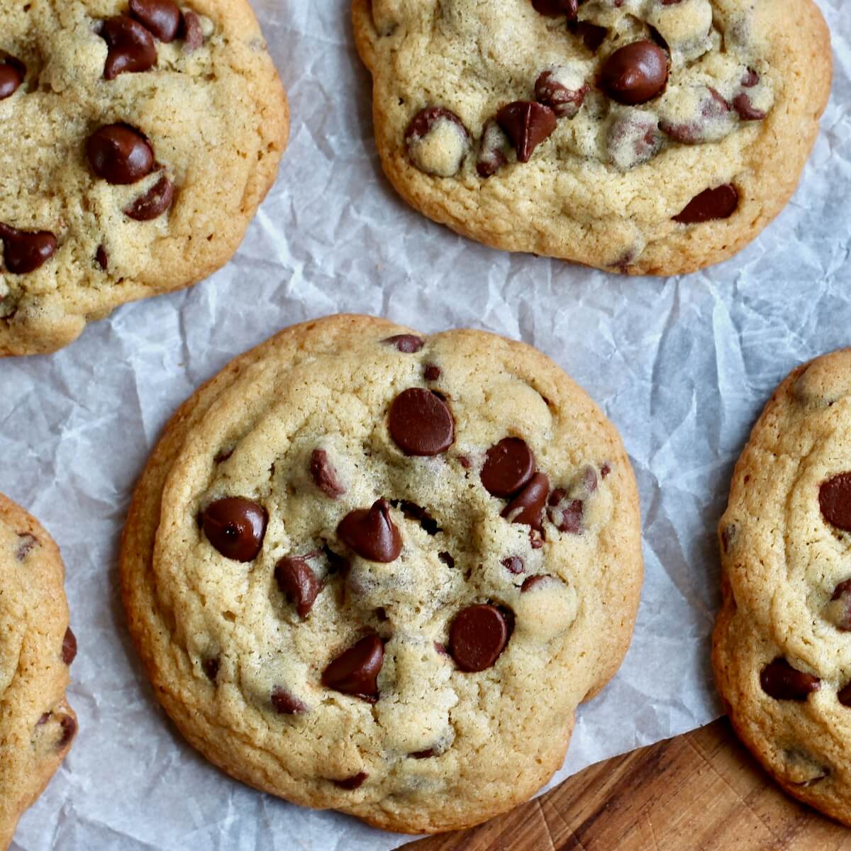 Sourdough chocolate chip cookies on a sheet of wrinkly parchment paper.