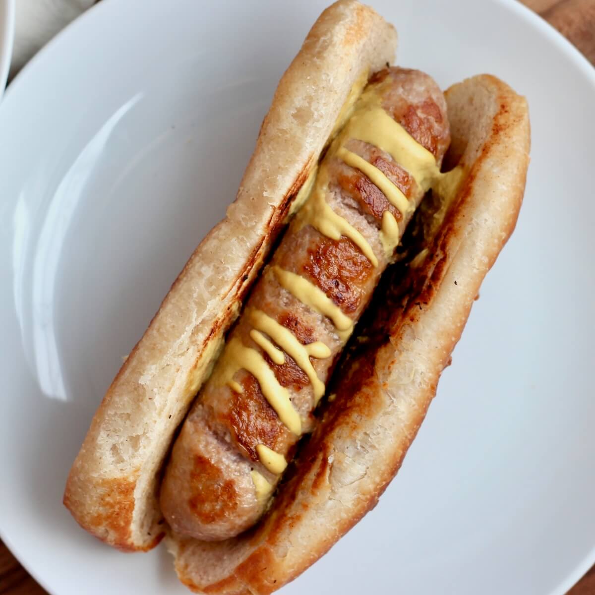 A turkey sausage with mustard on a sourdough hot dog bun.