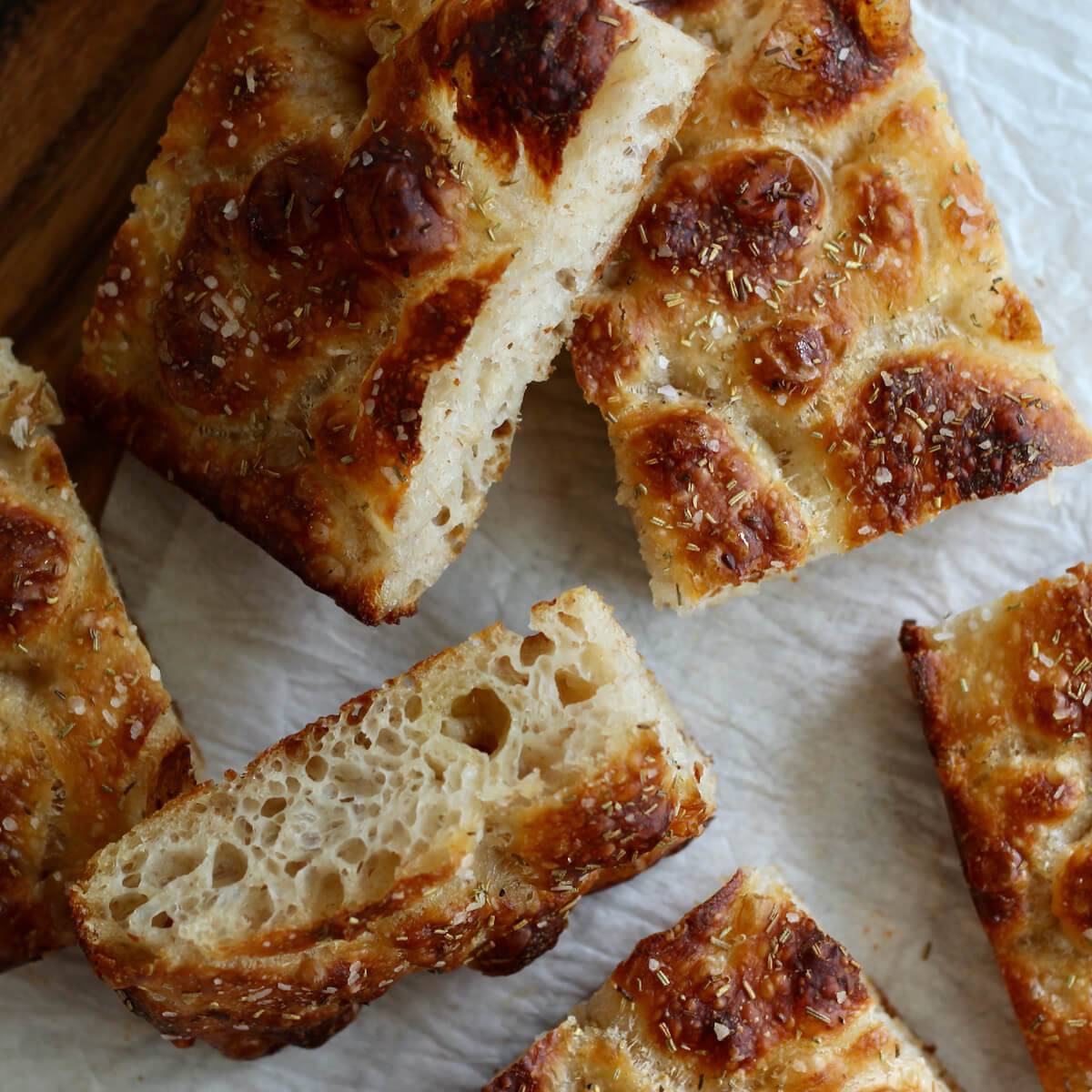 Pieces of sourdough focaccia bread on a piece of parchment paper.