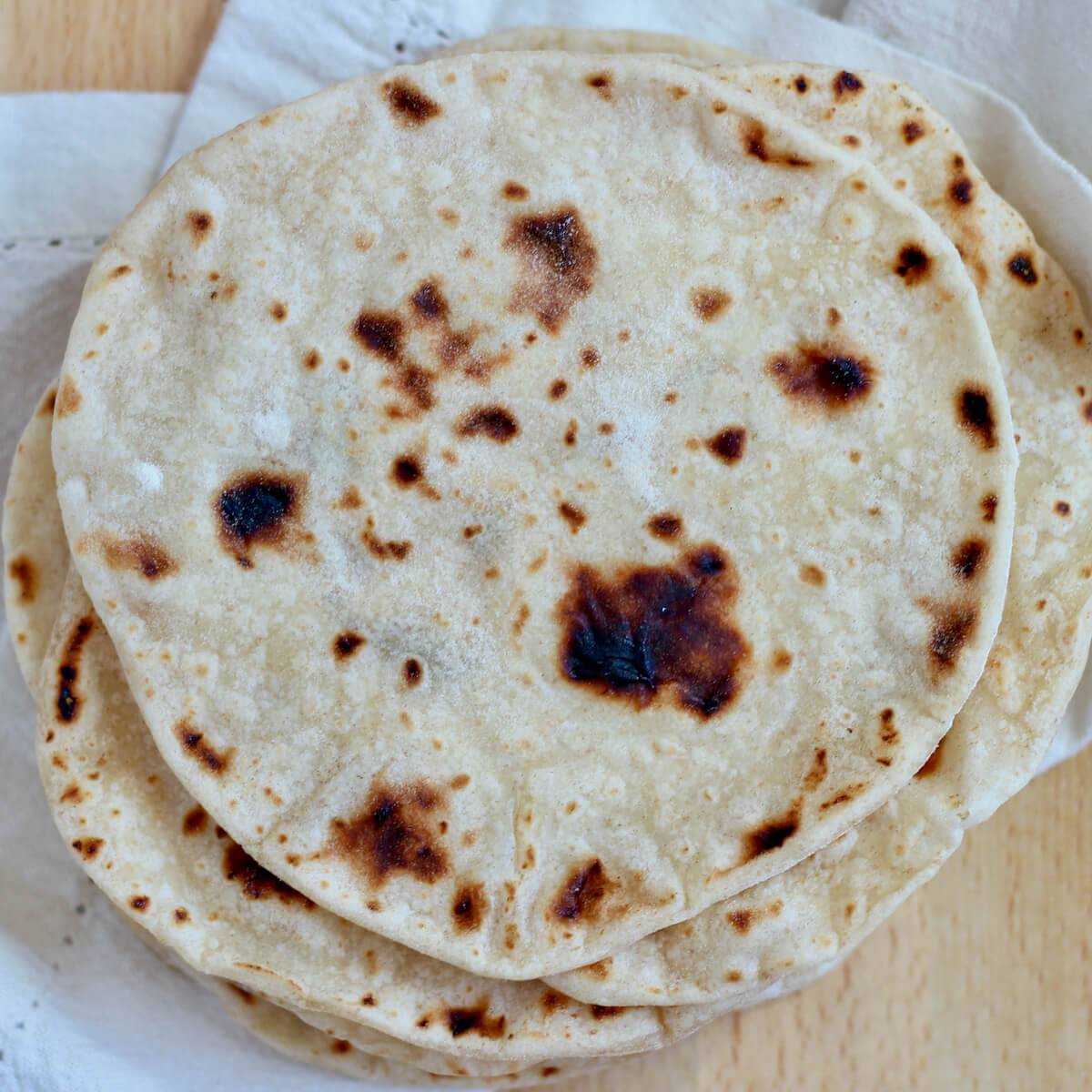 A stack of homemade sourdough tortillas.