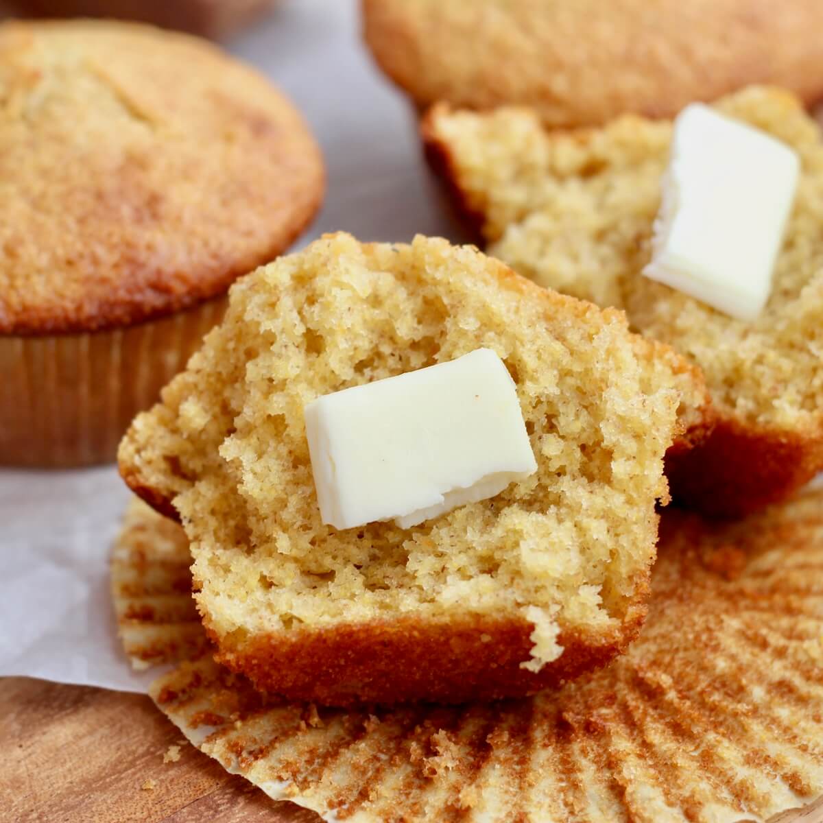 A sourdough cornbread muffin split in half with butter on it.