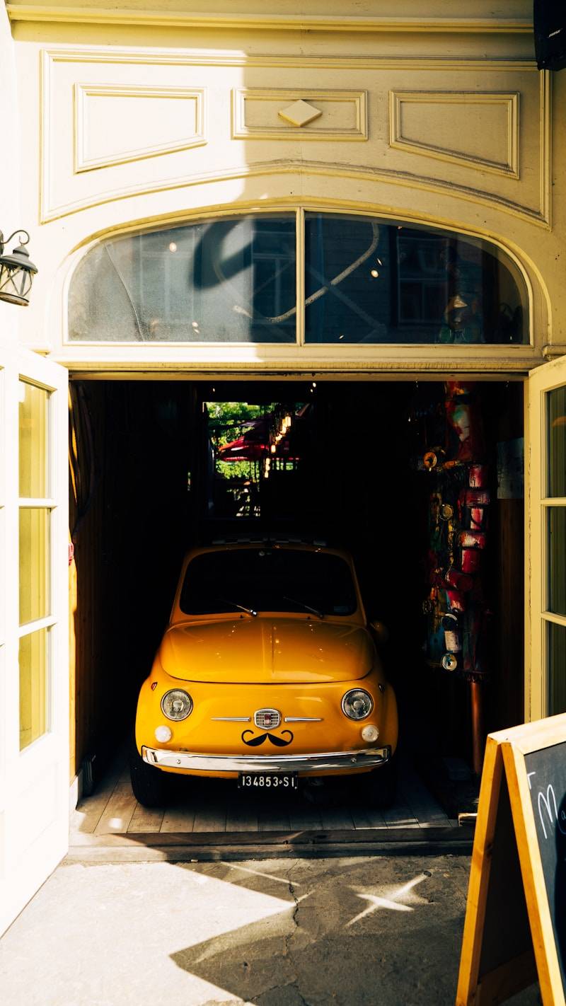 A yellow car is parked in a shaded doorway.