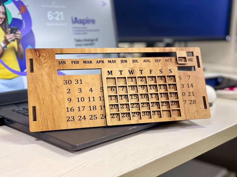 a wooden calendar sitting on top of a laptop computer