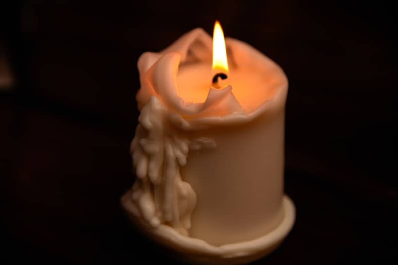 A lit candle with melting wax drips.