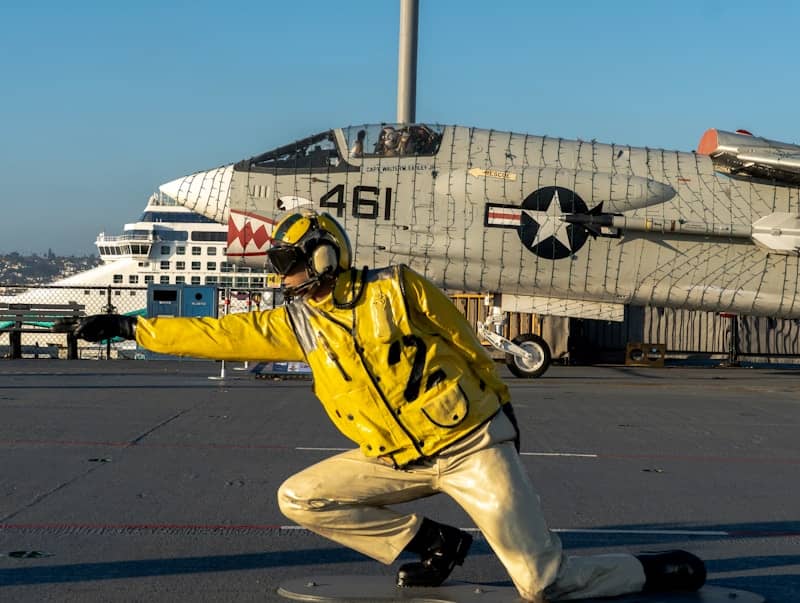 Deck crew directs aircraft on an aircraft carrier deck.