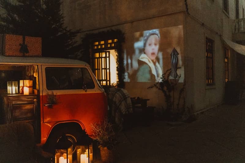 Red van parked outside building with movie projected on wall