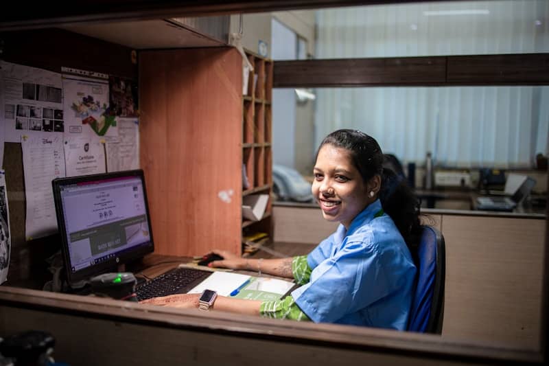 Woman working at a desk, smiling.