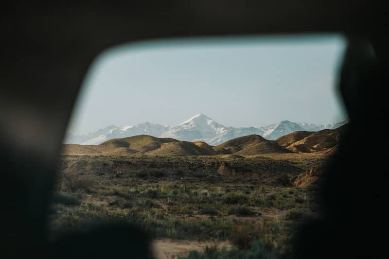 Snow-capped mountains viewed through a car window.