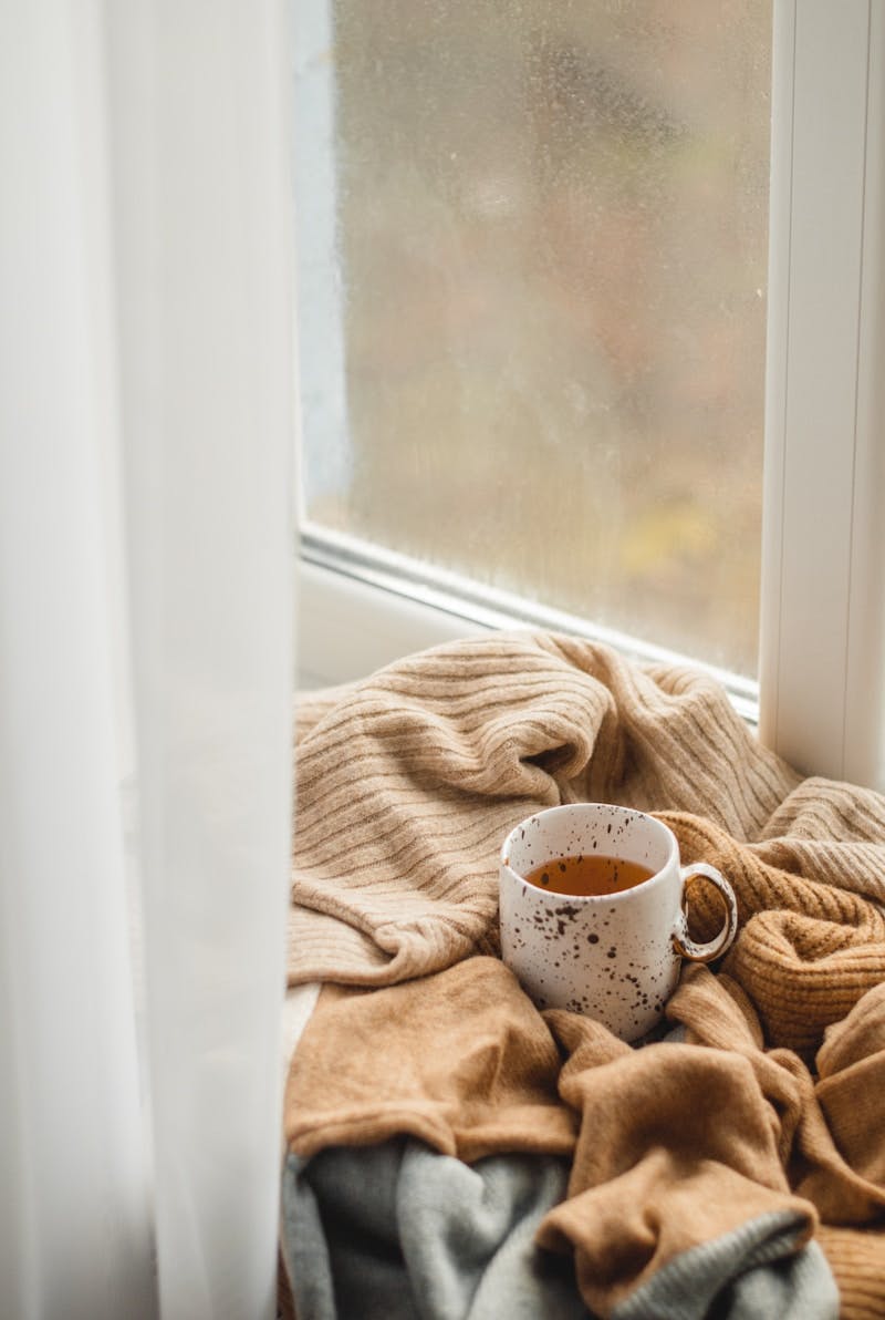 white ceramic mug on brown textile