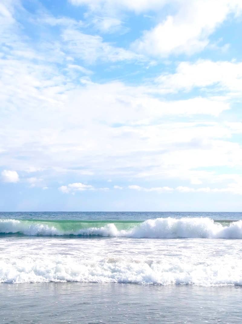 Waves crash on a beach under a blue sky.