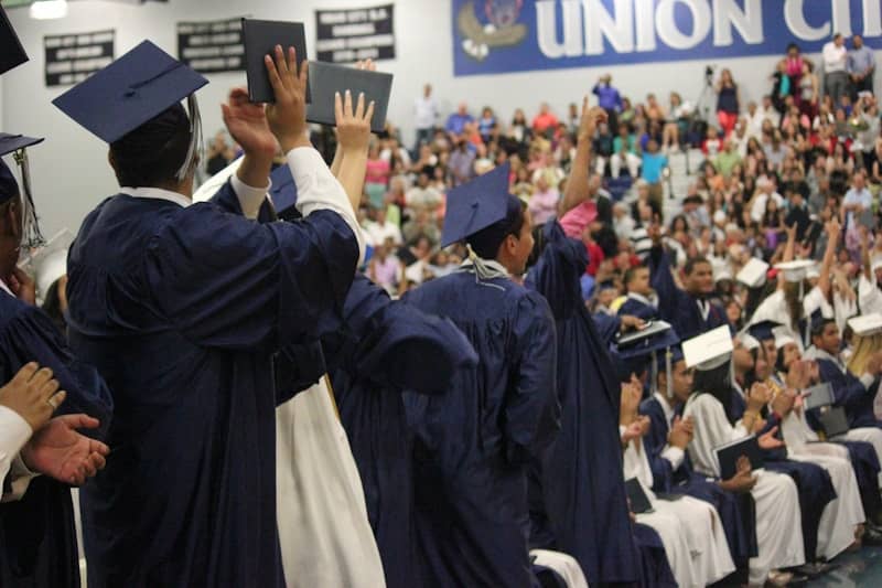 A group of people in graduation gowns standing in front of a crowd