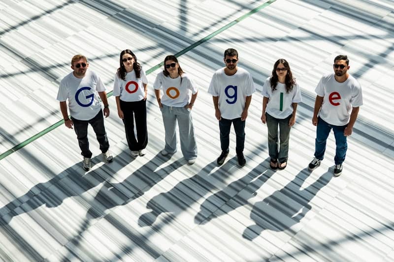 Six people wearing shirts spelling out google