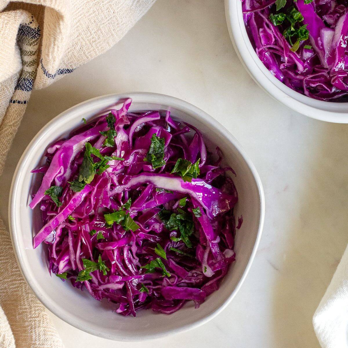 Red cabbage salad topped with black pepper and olive oil dressing.