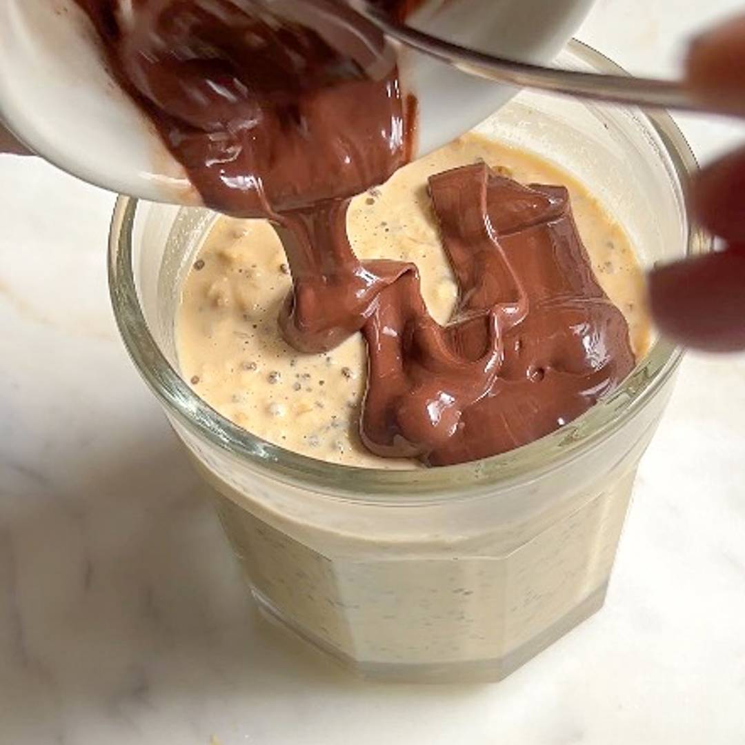 Pouring melted chocolate over chia overnight oats in a jar