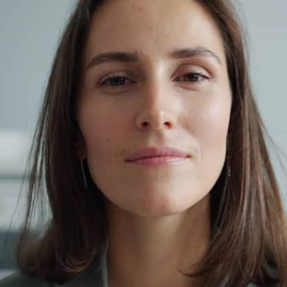 A woman with brown hair wearing a gray blazer