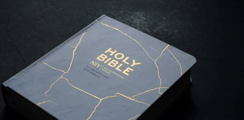 A white Bible with gold marble design.