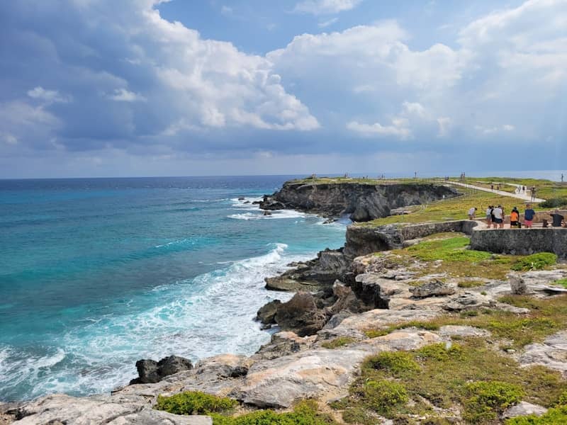 A group of people standing on top of a cliff next to the ocean