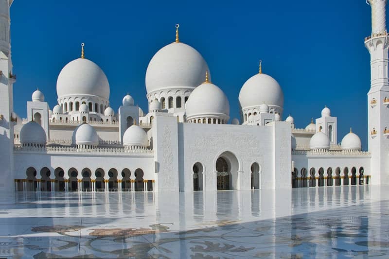 Grand white mosque with domes against blue sky