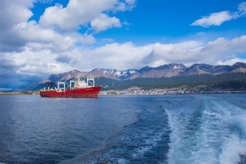 A red ship sails on a blue sea.