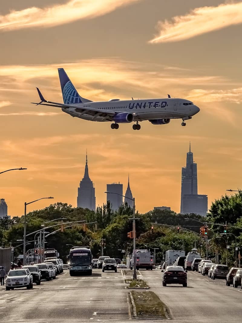 United airplane flying over city skyline at sunset