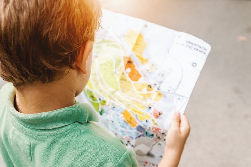 boy standing while reading map