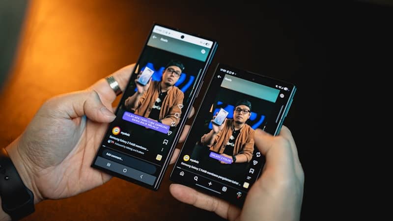 Hands hold two smartphones showing identical screen content.