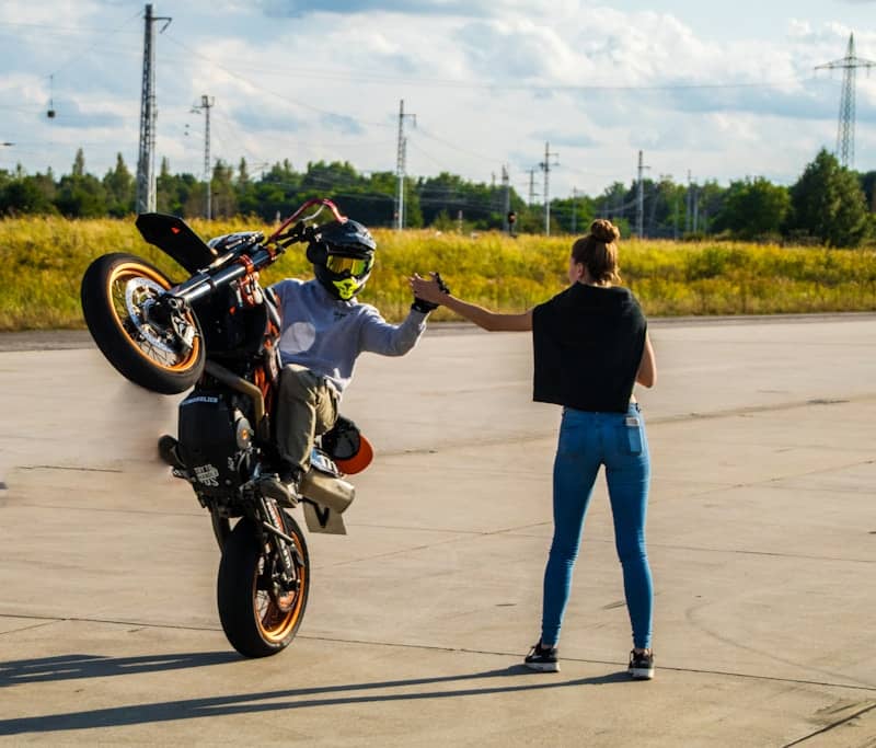 man in black t-shirt and blue denim jeans riding motorcycle on road during daytime