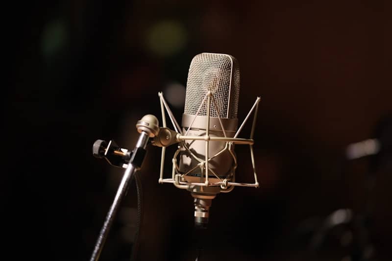 Vintage gold condenser microphone against a dark background.