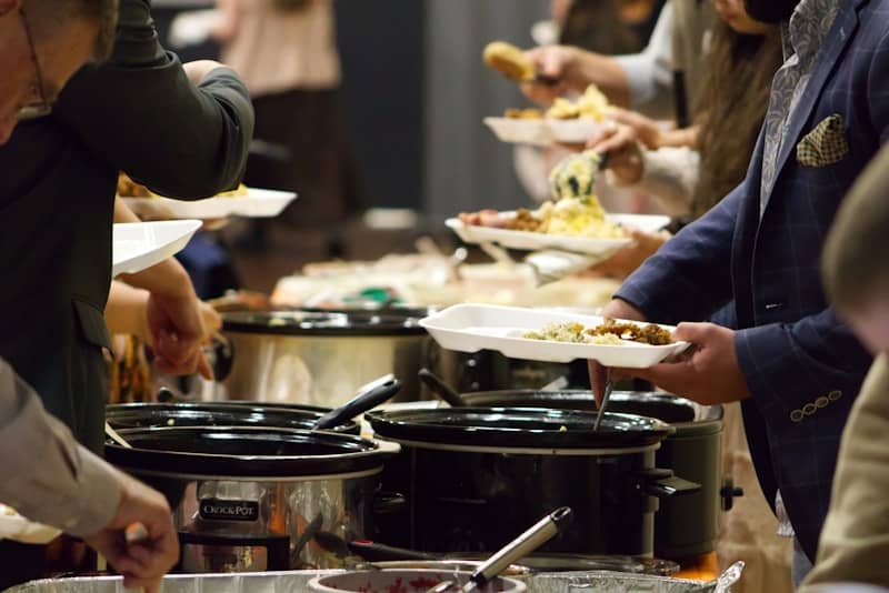 A group of people standing around a buffet line