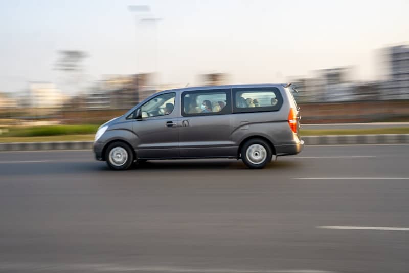A grey van moves quickly down the road.