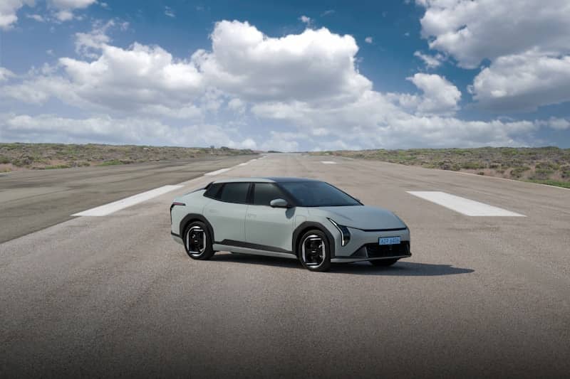 A light-colored car is driving on a runway.
