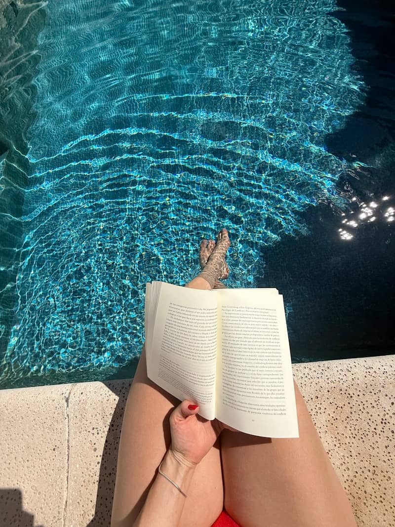 Person reading a book by the swimming pool