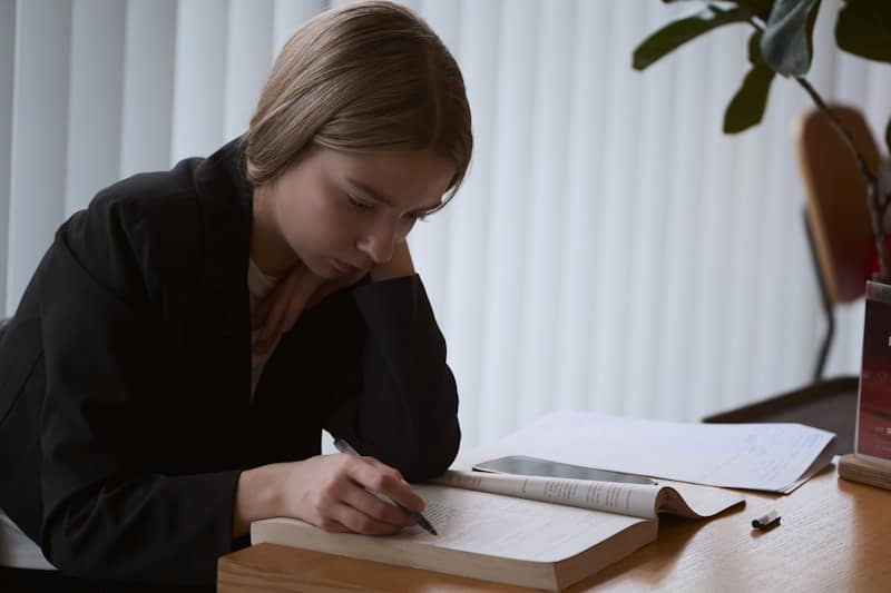 Young woman studying at a desk with an open book.