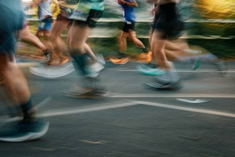 A group of runners in motion on a paved road with long exposure blur