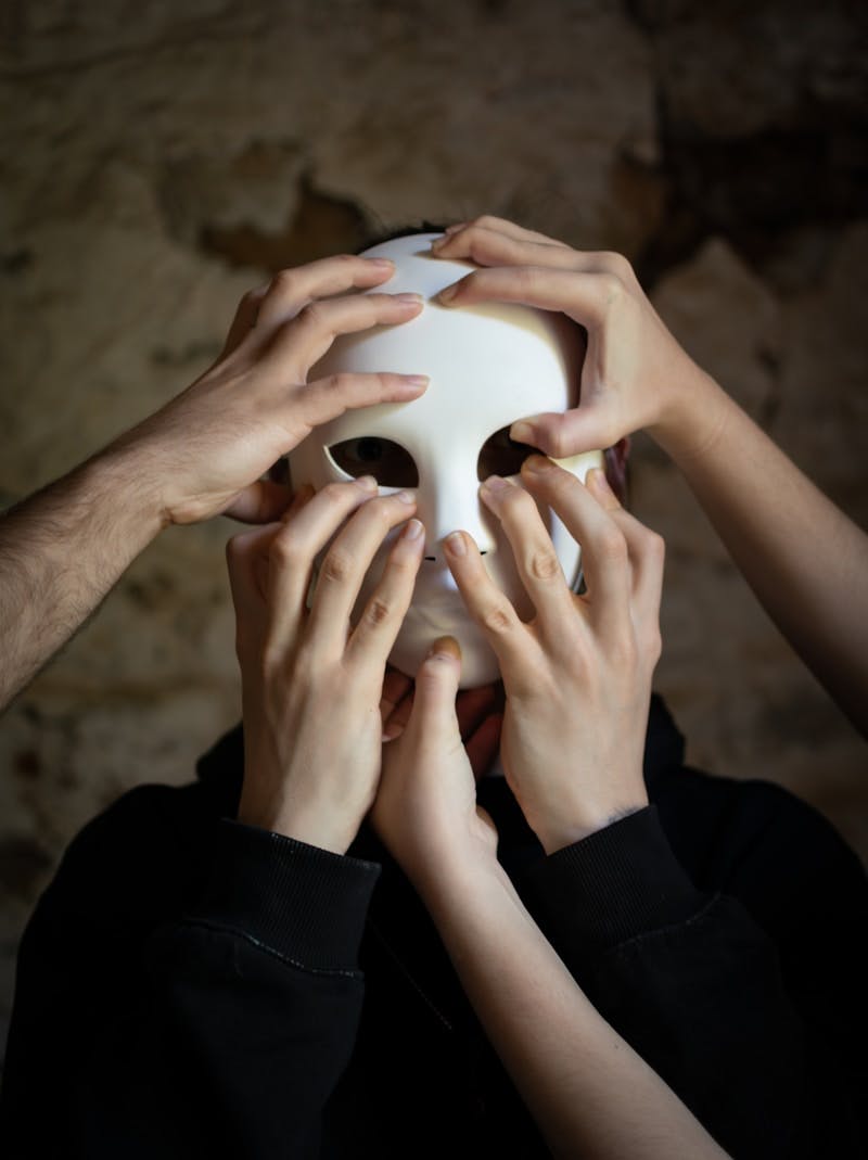 A group of people holding up a white mask