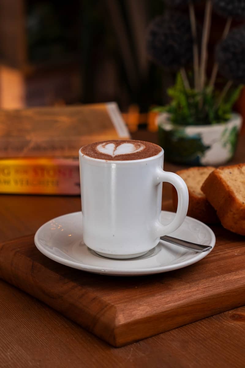 A white mug with latte art sits on a saucer.