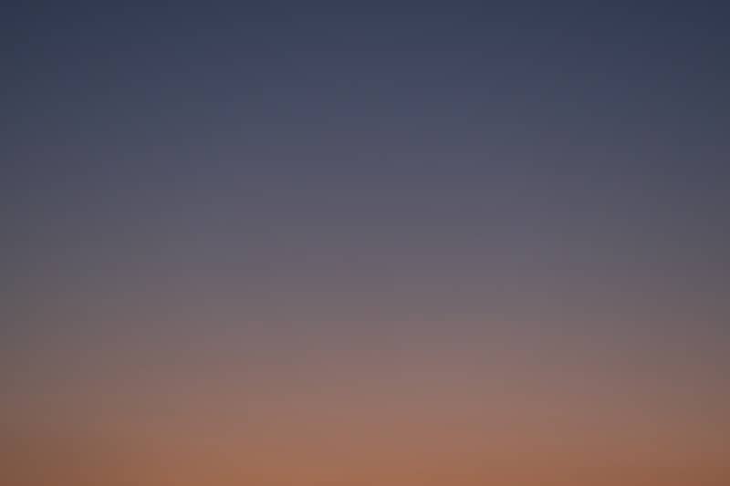 A gradient sky transitioning from dark blue to orange.