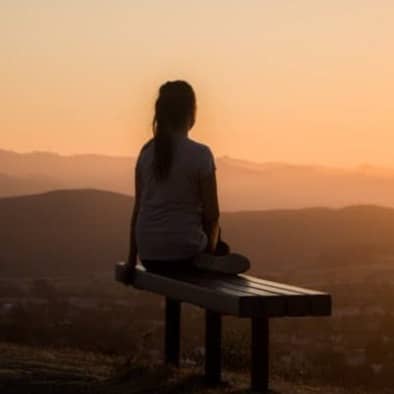 woman sitting on bench over viewing mountain