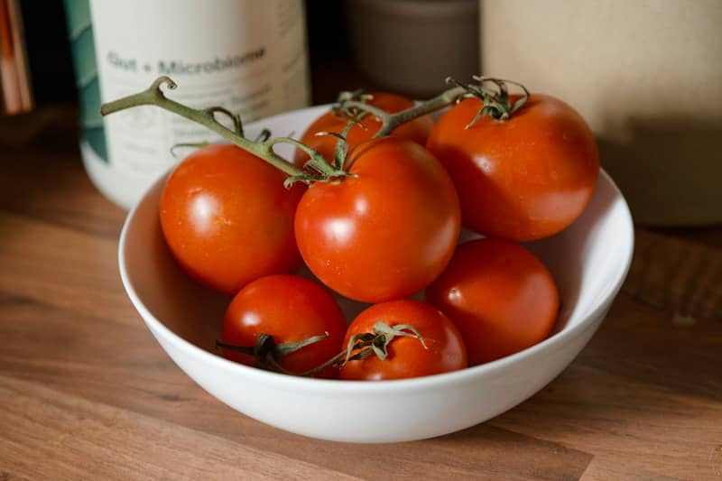 Fresh red tomatoes in a white bowl.